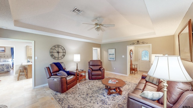 living room with visible vents, a raised ceiling, ceiling fan, and baseboards