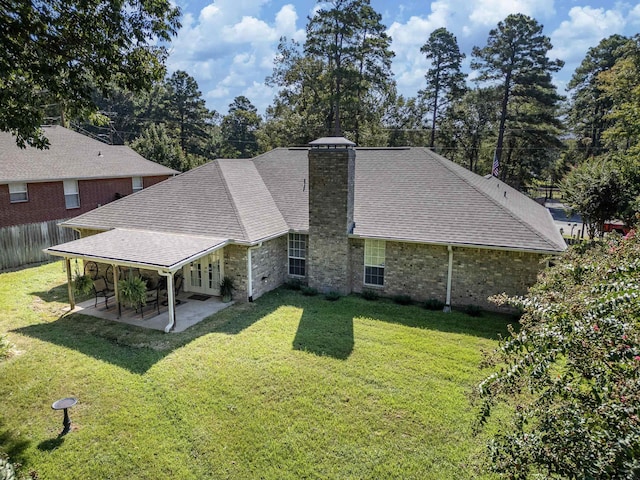 back of house with a lawn, a patio, a chimney, and a shingled roof