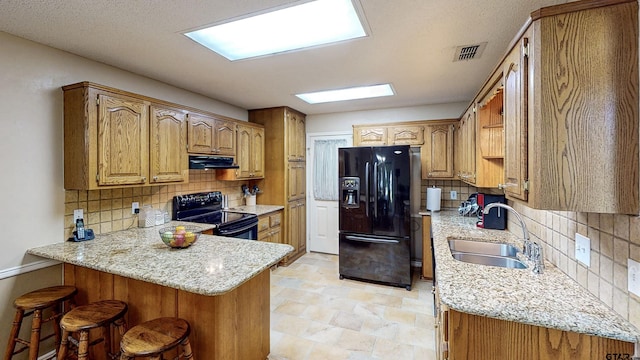 kitchen featuring visible vents, a peninsula, range hood, a sink, and black appliances