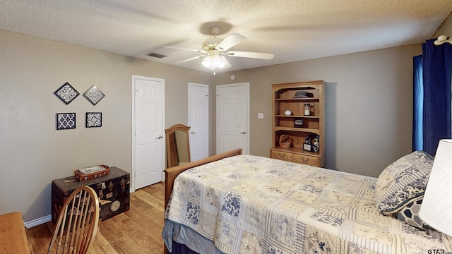 bedroom featuring a textured ceiling, light wood-style flooring, a ceiling fan, baseboards, and visible vents