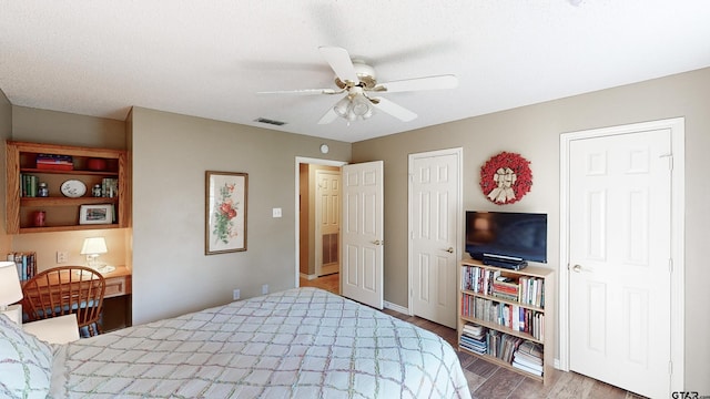 bedroom with a ceiling fan, baseboards, visible vents, and wood finished floors