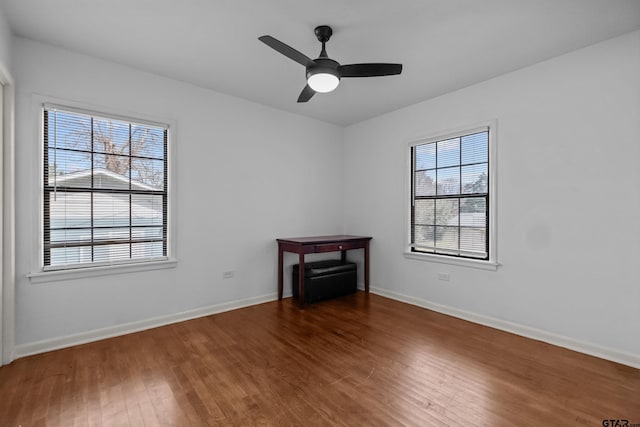 empty room with ceiling fan, wood finished floors, and baseboards