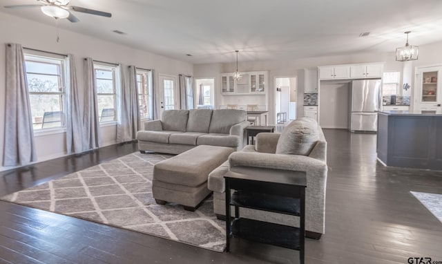 living room with dark hardwood / wood-style flooring and ceiling fan with notable chandelier