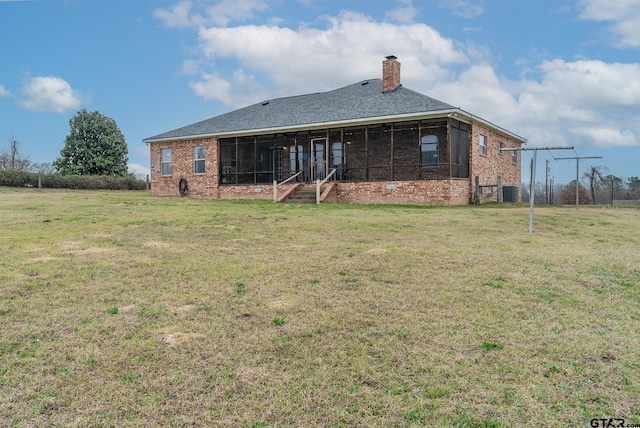 rear view of house featuring a yard and a sunroom