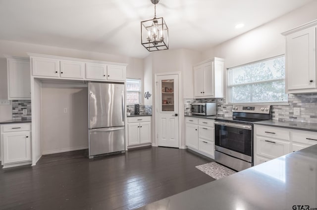 kitchen with appliances with stainless steel finishes, a wealth of natural light, pendant lighting, white cabinetry, and dark hardwood / wood-style flooring