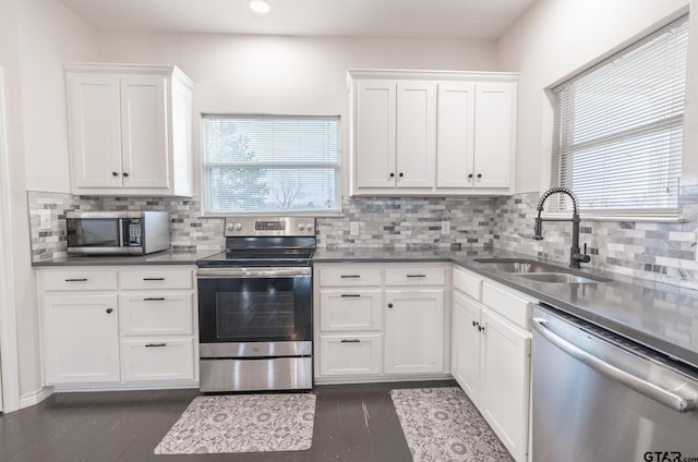 kitchen with appliances with stainless steel finishes, sink, white cabinets, and dark hardwood / wood-style flooring