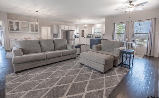 living room with ceiling fan with notable chandelier and dark hardwood / wood-style floors