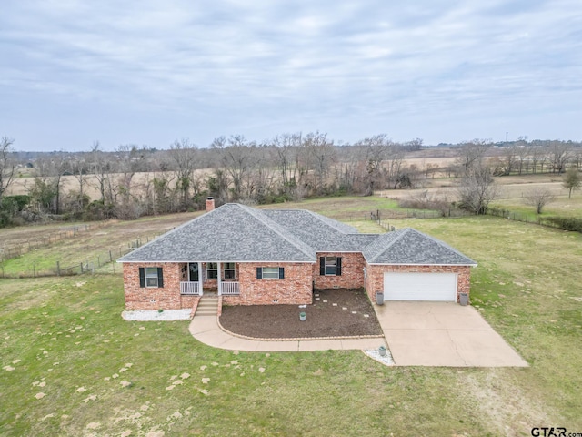 ranch-style home with a garage, a front yard, covered porch, and a rural view