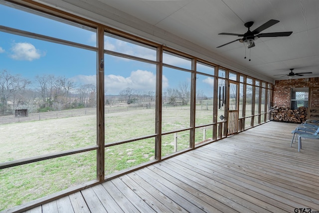 unfurnished sunroom with ceiling fan, a rural view, and a wealth of natural light