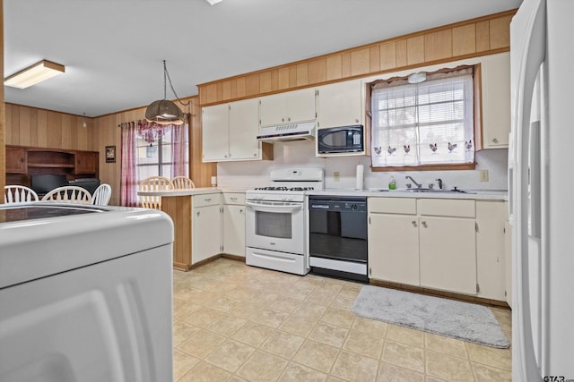 kitchen featuring wood walls, white cabinetry, black appliances, a healthy amount of sunlight, and decorative light fixtures