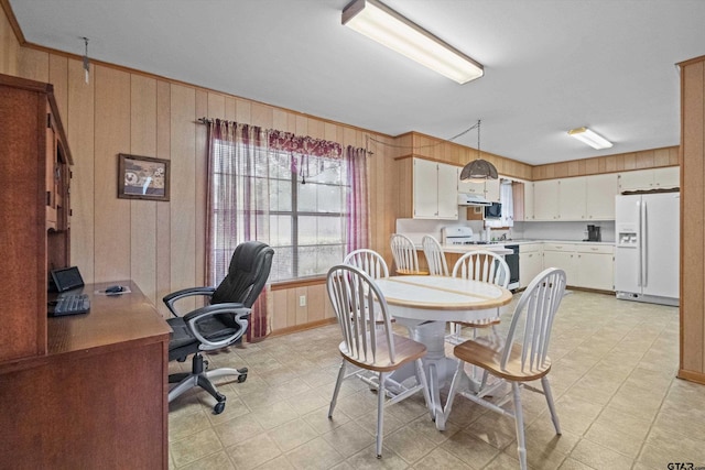 dining space featuring ornamental molding and wooden walls