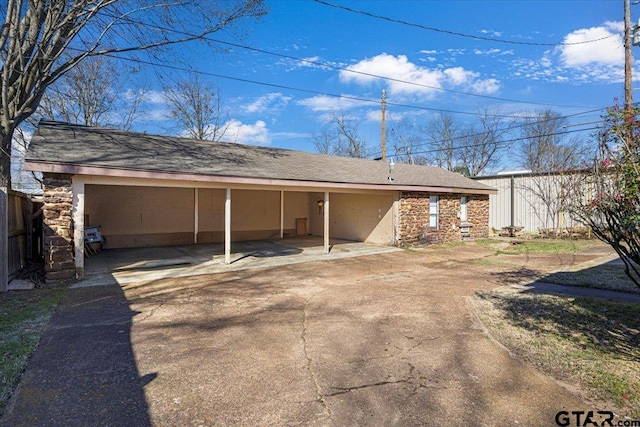 exterior space with driveway, stone siding, and a carport