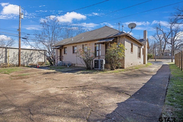 view of property exterior with brick siding, fence, and central air condition unit