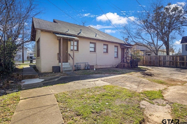 back of house with entry steps, fence, and brick siding