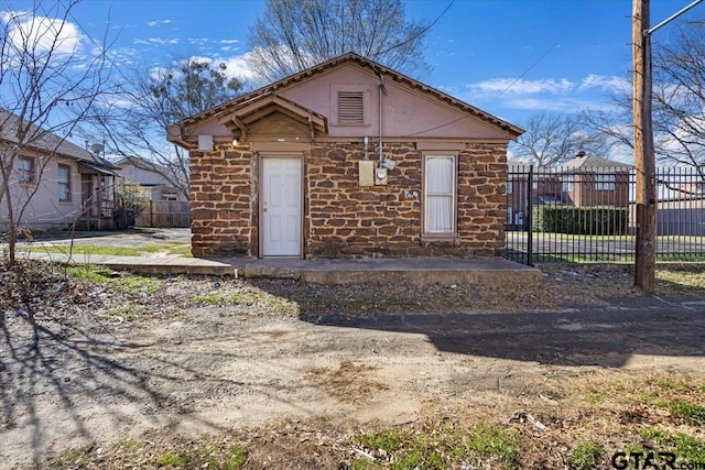 view of front of home featuring stone siding, a patio, and fence