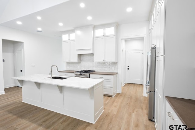 9244 Villas Ct, Tyler, TX 75703 - kitchen featuring a sink, appliances with stainless steel finishes, premium range hood, backsplash, and light wood-style flooring
