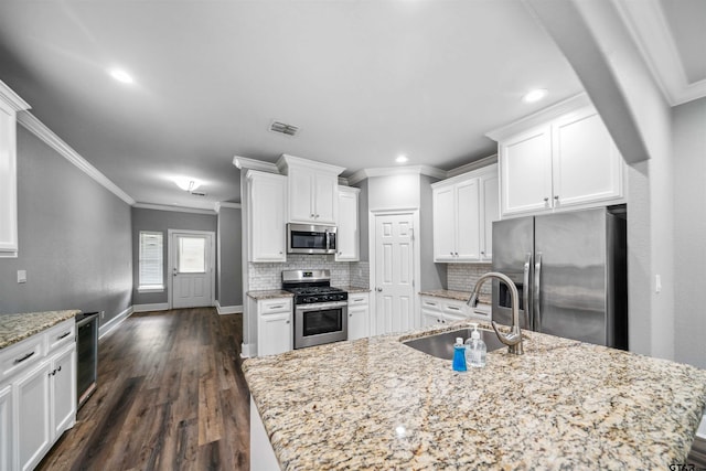 811 W 27th St, Tyler, TX 75702 - kitchen featuring stainless steel appliances, a sink, ornamental molding, backsplash, and white cabinetry
