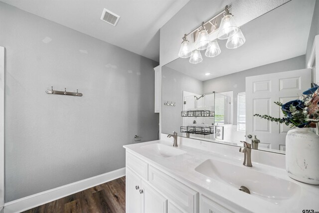 811 W 27th St, Tyler, TX 75702 - bathroom featuring a stall shower, wood finished floors, baseboards, and double vanity