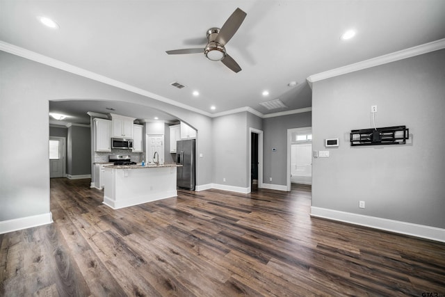 811 W 27th St, Tyler, TX 75702 - kitchen featuring appliances with stainless steel finishes, ceiling fan, white cabinets, arched walkways, and a kitchen island with sink