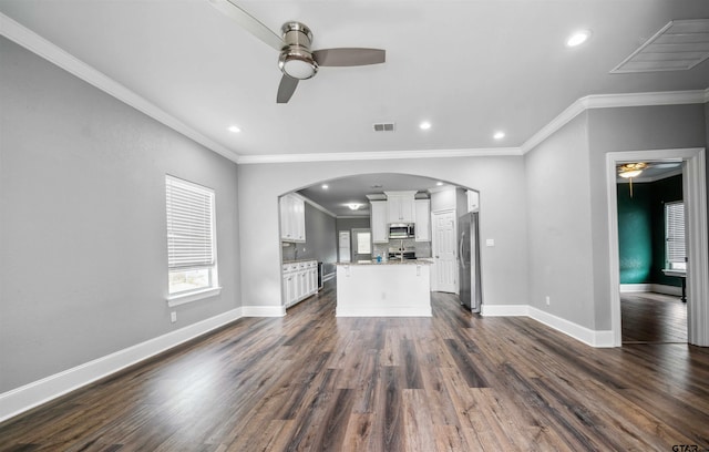 811 W 27th St, Tyler, TX 75702 - unfurnished living room featuring a ceiling fan, arched walkways, dark wood finished floors, ornamental molding, and baseboards