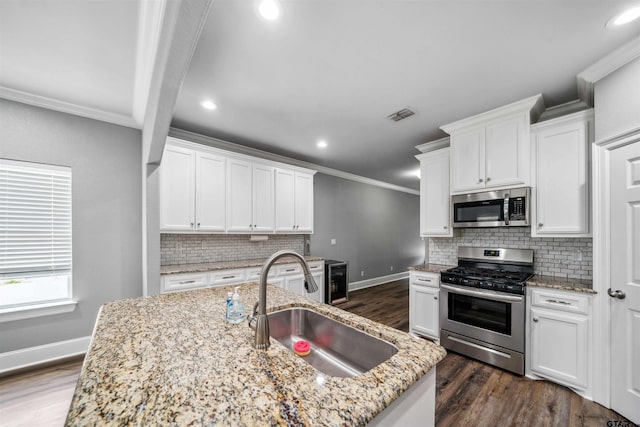 811 W 27th St, Tyler, TX 75702 - kitchen with appliances with stainless steel finishes, a sink, ornamental molding, dark wood-style floors, and backsplash