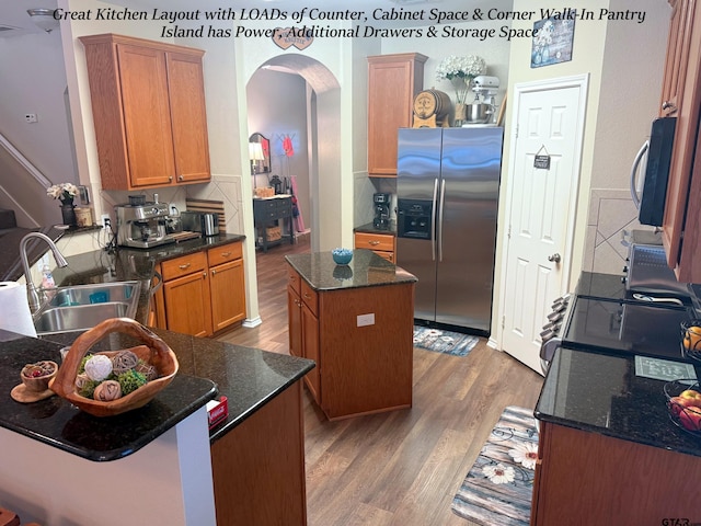 12260 Wild Horse, Tyler, TX 75706 - kitchen with arched walkways, light wood finished floors, stainless steel appliances, a center island, and dark stone counters