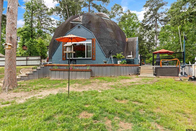exterior space with a lawn, a wooden deck, a shingled roof, and a gambrel roof