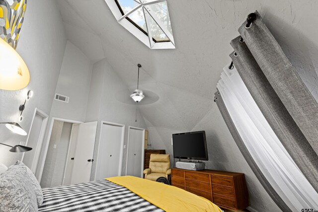 bedroom featuring two closets, lofted ceiling with skylight, and visible vents
