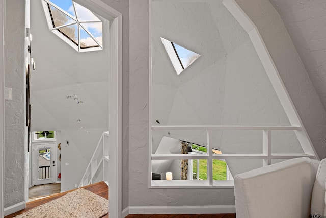 interior details with a skylight, baseboards, a textured wall, and wood finished floors