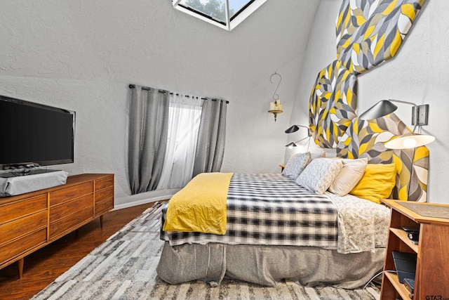 bedroom featuring a skylight, a textured wall, and wood finished floors