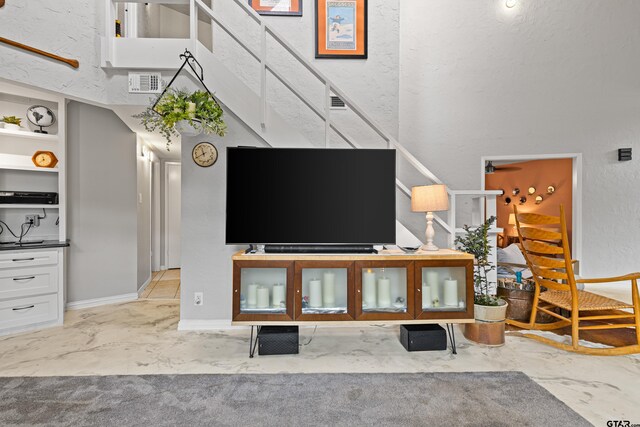 living area featuring stairway, a textured wall, and visible vents