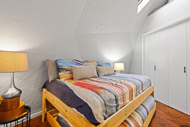 bedroom with vaulted ceiling, wood finished floors, and a closet