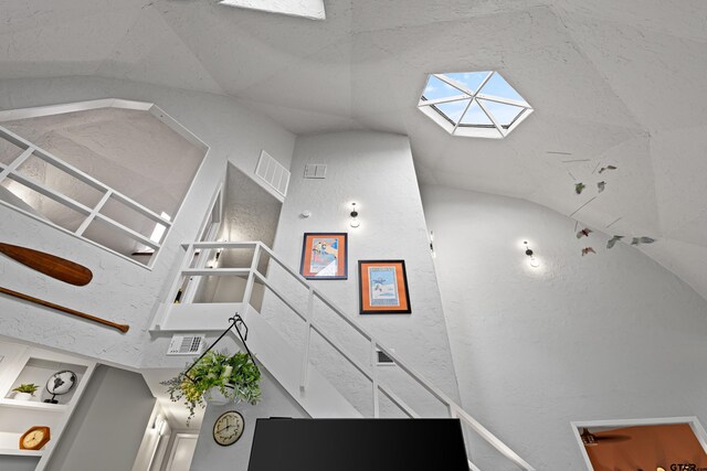 stairs featuring visible vents and lofted ceiling with skylight