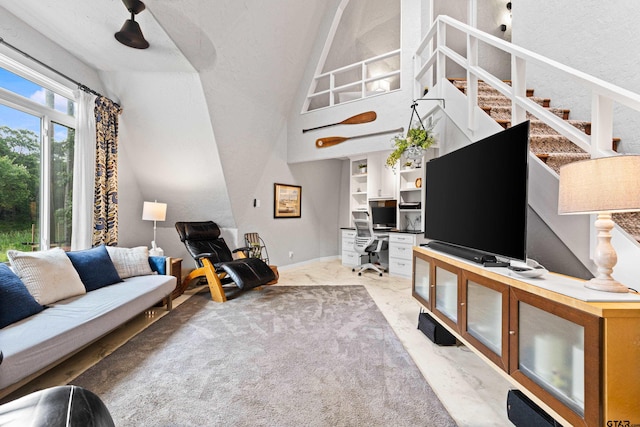 living room featuring baseboards, vaulted ceiling, and stairway
