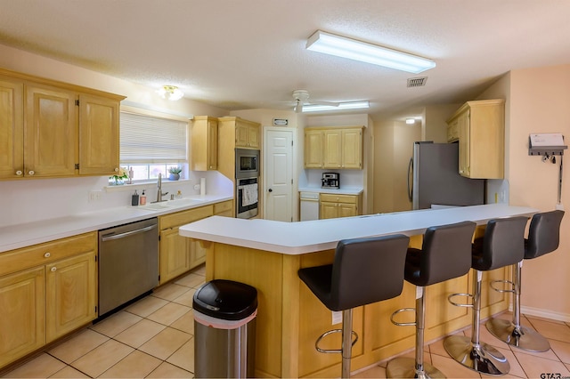 kitchen with sink, a kitchen bar, light tile patterned floors, and stainless steel appliances