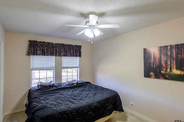 bedroom with a textured ceiling, light colored carpet, and ceiling fan