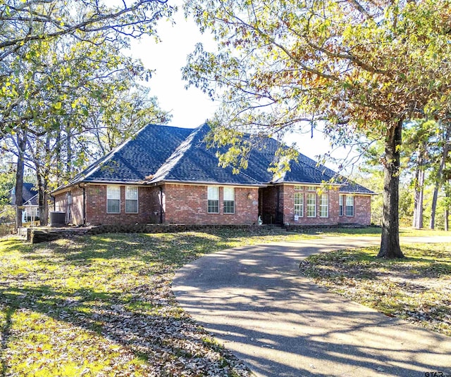 ranch-style house with central air condition unit and a front lawn