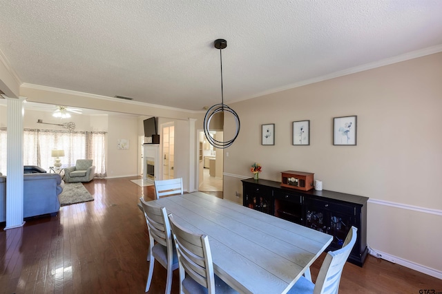 dining space with ornamental molding, dark hardwood / wood-style floors, a textured ceiling, ceiling fan, and decorative columns