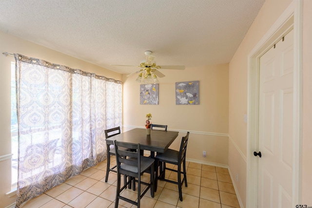 dining area with a textured ceiling, light tile patterned floors, and ceiling fan