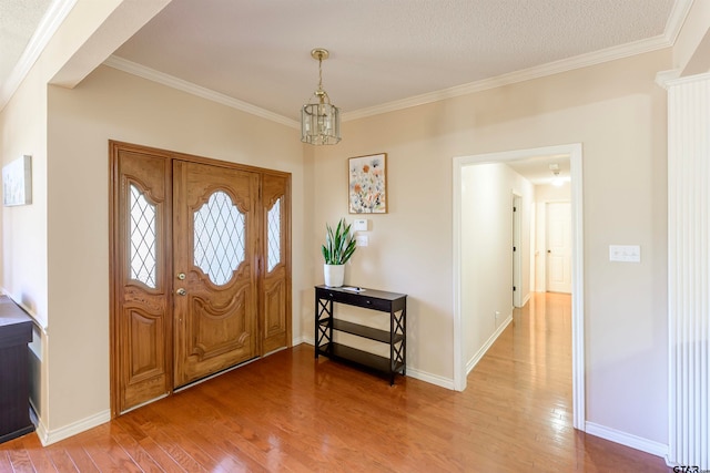 foyer entrance with a chandelier, a textured ceiling, hardwood / wood-style flooring, and crown molding