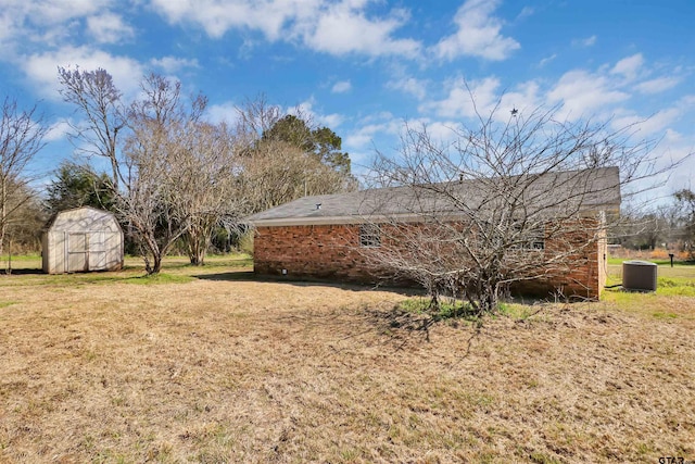 view of property exterior with a storage shed, a yard, central air condition unit, an outdoor structure, and brick siding