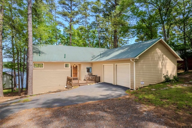 ranch-style house featuring metal roof, an attached garage, and aphalt driveway