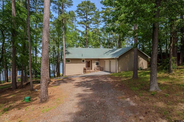 ranch-style home featuring driveway, metal roof, and a garage