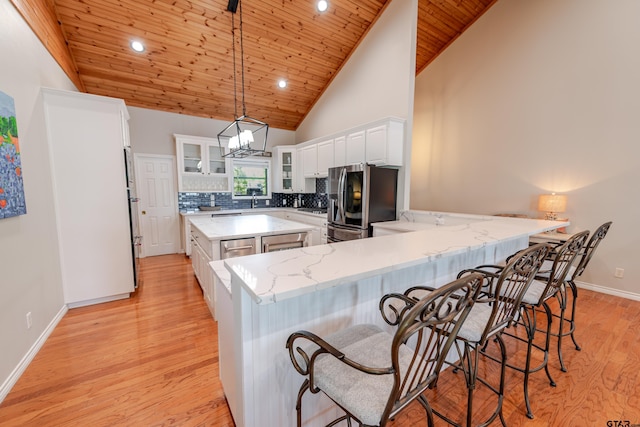 kitchen with white cabinets, a peninsula, tasteful backsplash, light wood-type flooring, and stainless steel refrigerator with ice dispenser