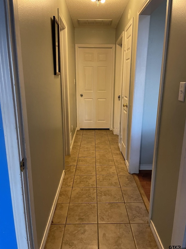 hallway featuring tile patterned floors and a textured ceiling