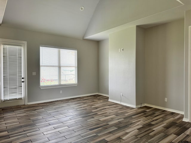 spare room with dark wood-type flooring and vaulted ceiling