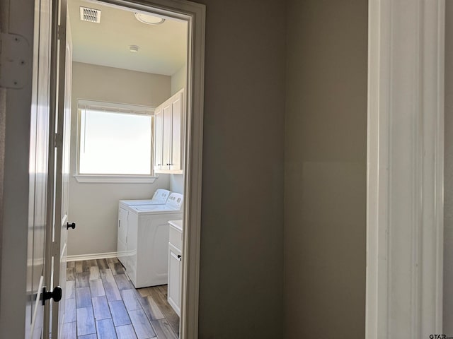 laundry room featuring washer and clothes dryer, cabinets, and light hardwood / wood-style flooring