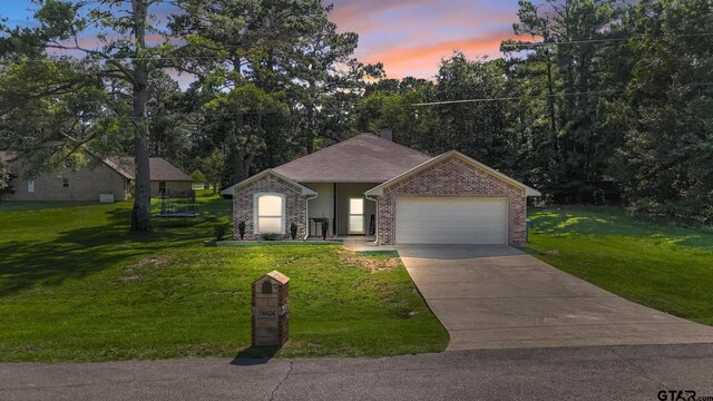 18424 Whipporwill, Flint, TX 75762 - view of front of house with an attached garage, a front yard, concrete driveway, and brick siding