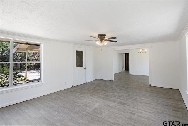 empty room featuring hardwood / wood-style floors, ceiling fan with notable chandelier, a textured ceiling, and crown molding