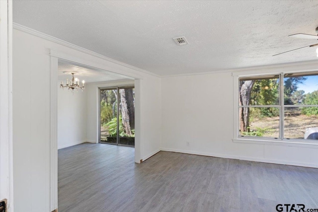 empty room featuring a textured ceiling, ceiling fan with notable chandelier, ornamental molding, and hardwood / wood-style flooring